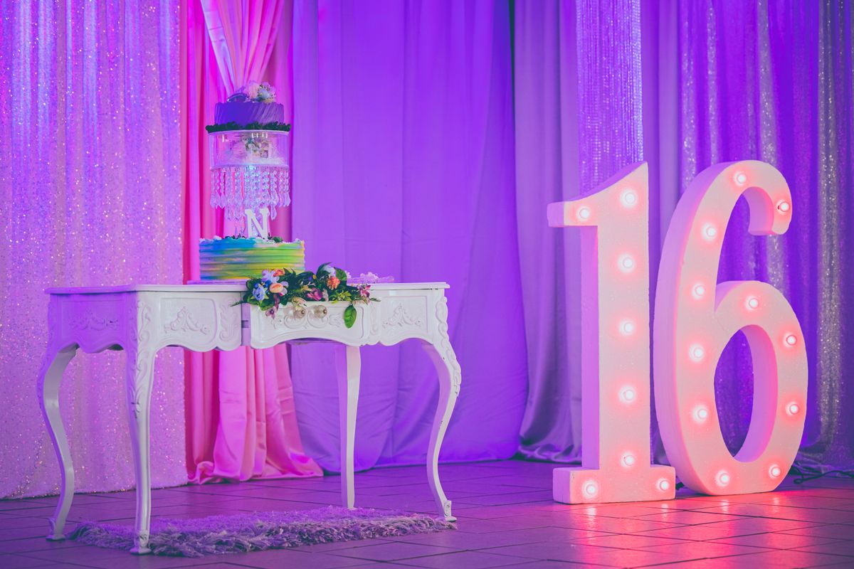 Vibrant sweet sixteen party decor with an elegant cake and illuminated number 16.